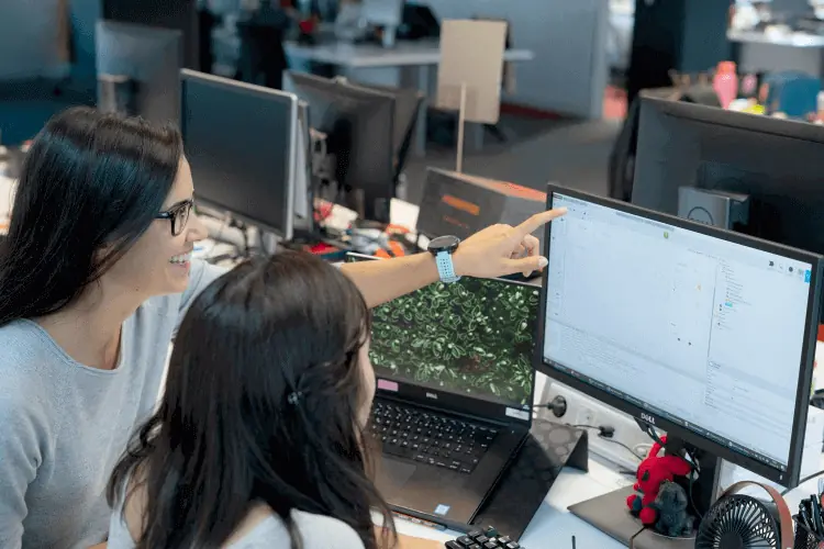 Sara showing something on a computer screen to a colleague.